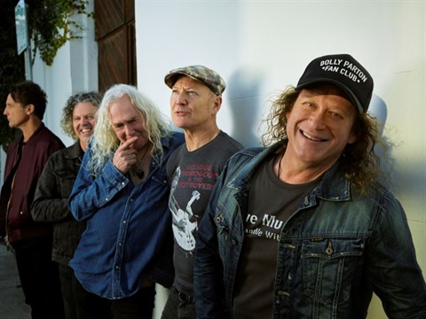 five male musicians leaning against a white wall with a dark timber door