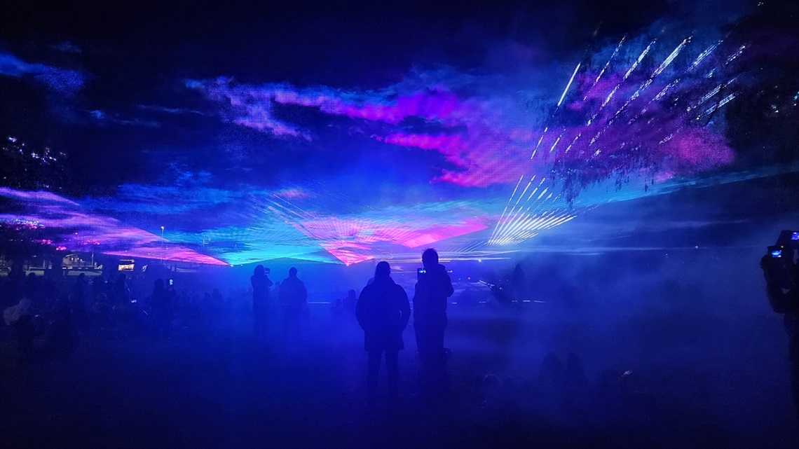 image of people standing around at an laser show event with blue lighting