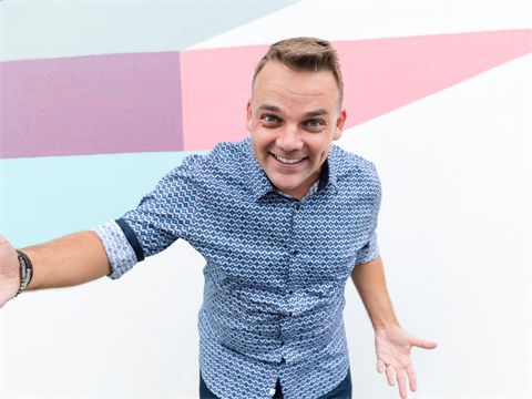 Peter Williams standing in front of coloured background with welcoming arms