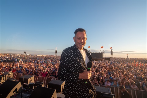 Mike Goldman standing on stage with the Mundi Mundi Bash crowd behind him