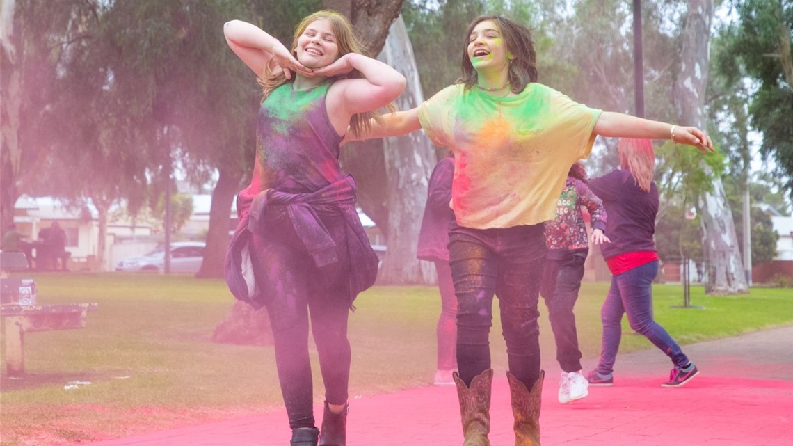 two teenage girls runnig through coloured chalk participating in a colour run